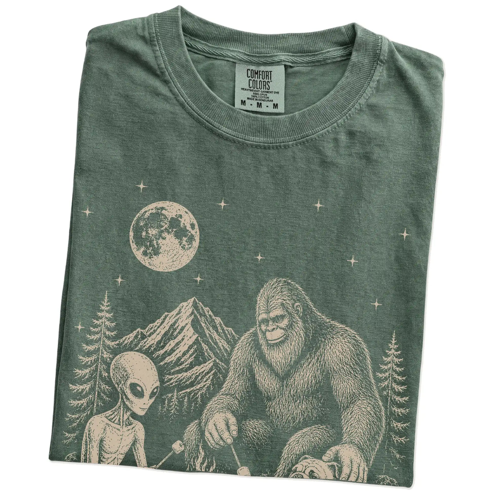 Folded Moss Comfort Colors® T-shirt showing Bulldog camping with Bigfoot and an alien