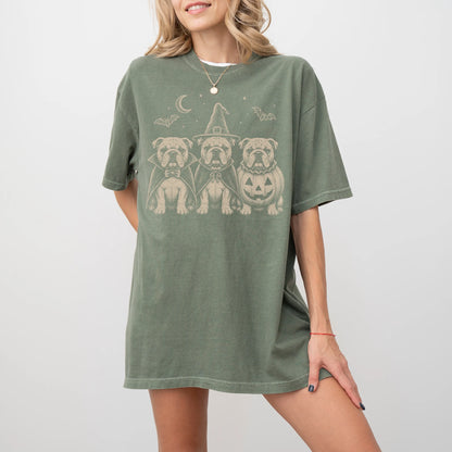 Model wearing a Moss Comfort Colors® T-shirt showing three Bulldog dogs dressed for Halloween beneath bats and a crescent moo