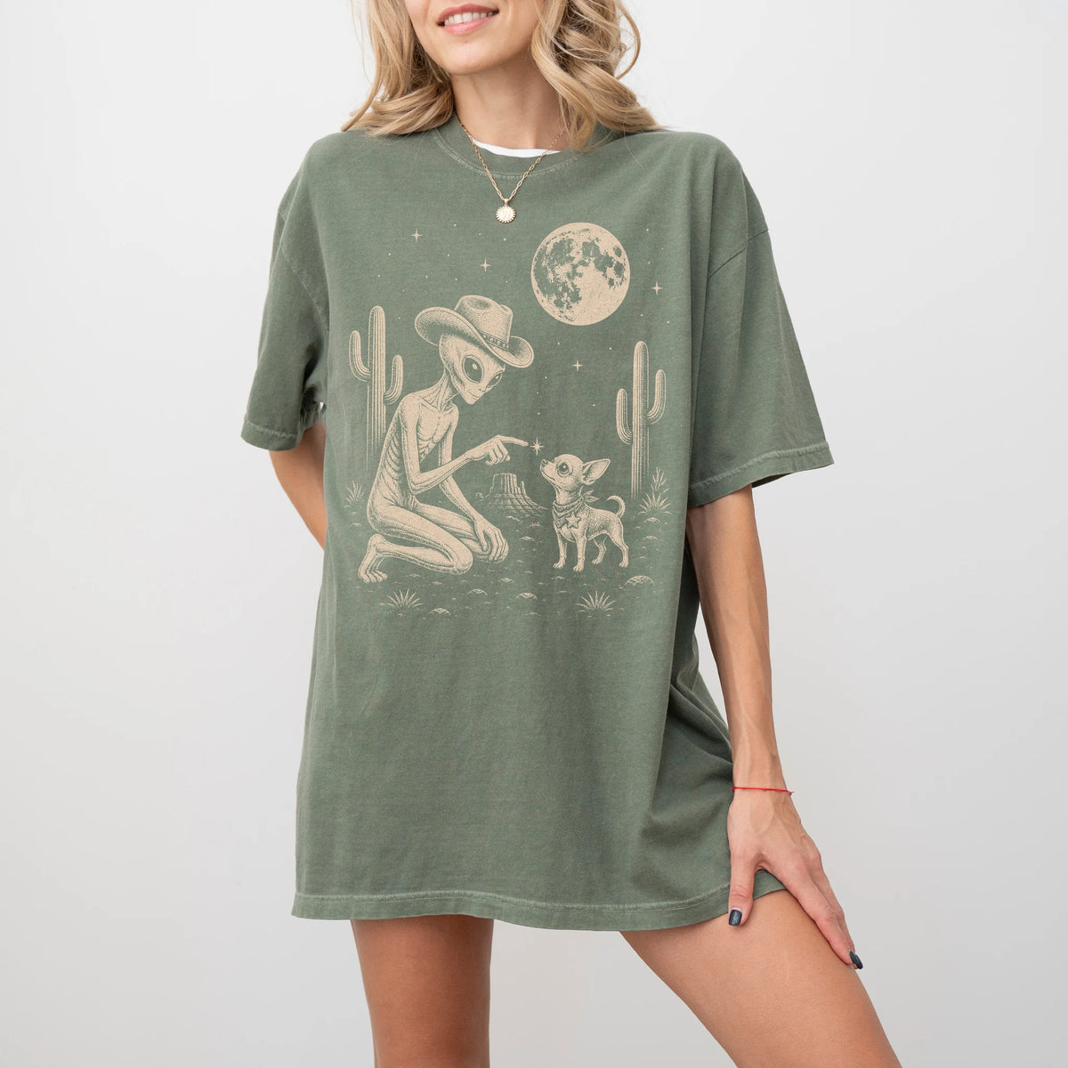 Model wearing a Moss Comfort Colors® T-shirt with cowboy alien fist-bumping a chihuahua beneath the moon