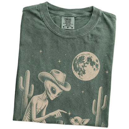 Folded Moss Comfort Colors® T-shirt showing cowboy alien fist-bumping a chihuahua beneath the moon