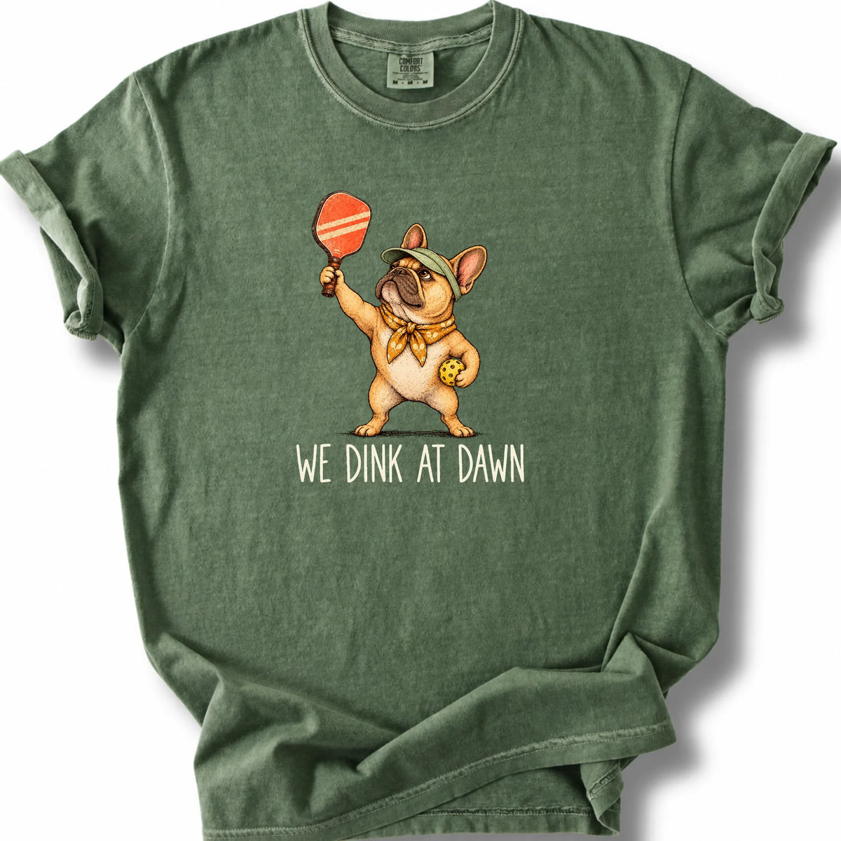 French Bulldog with a pickleball paddle and ball on a Moss Comfort Colors® T-shirt with We Dink at Dawn text