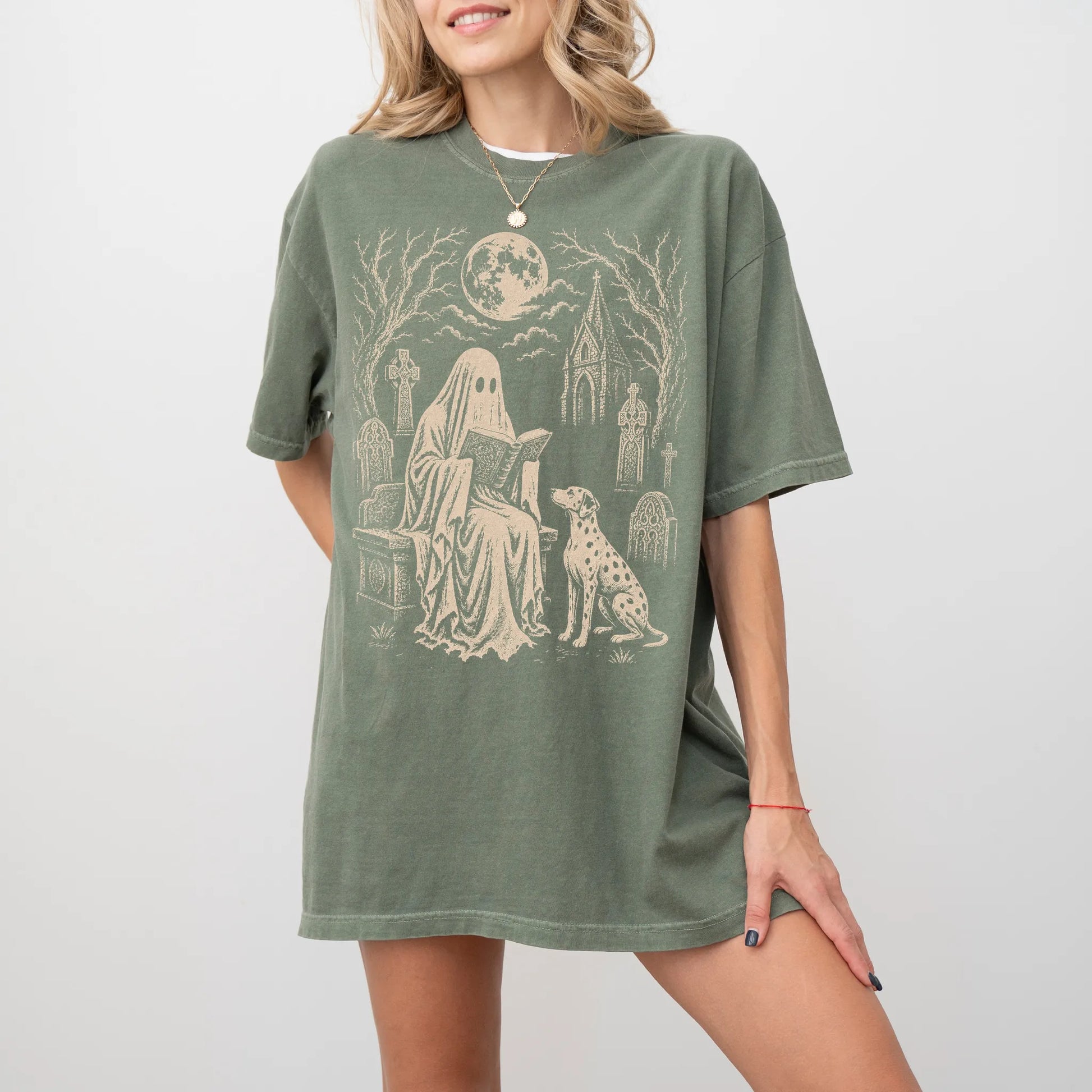 Model wearing a Moss Comfort Colors® T-shirt showing Dalmatian beside a reading ghost in a moonlit graveyard