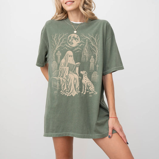 Model wearing a Moss Comfort Colors® T-shirt showing Dalmatian beside a reading ghost in a moonlit graveyard