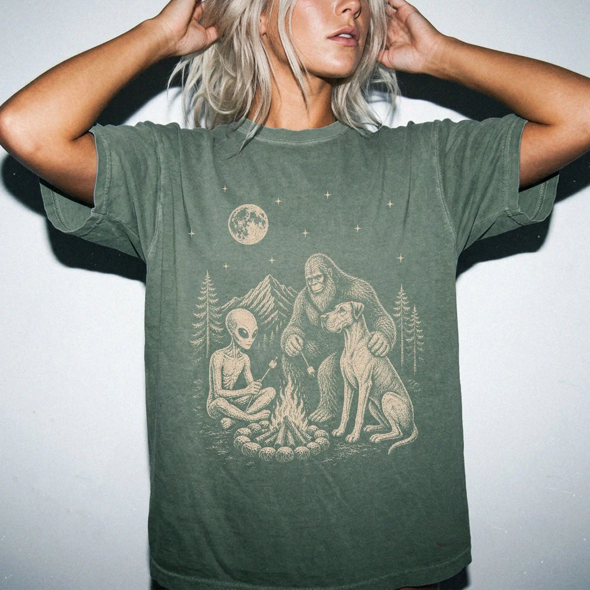 Model wearing a Moss Comfort Colors® T-shirt showing Great Dane camping with Bigfoot and an alien