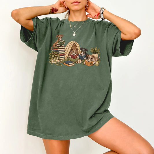Greyhound puppies reading books in a cozy blanket fort on a Moss T-shirt worn by a model