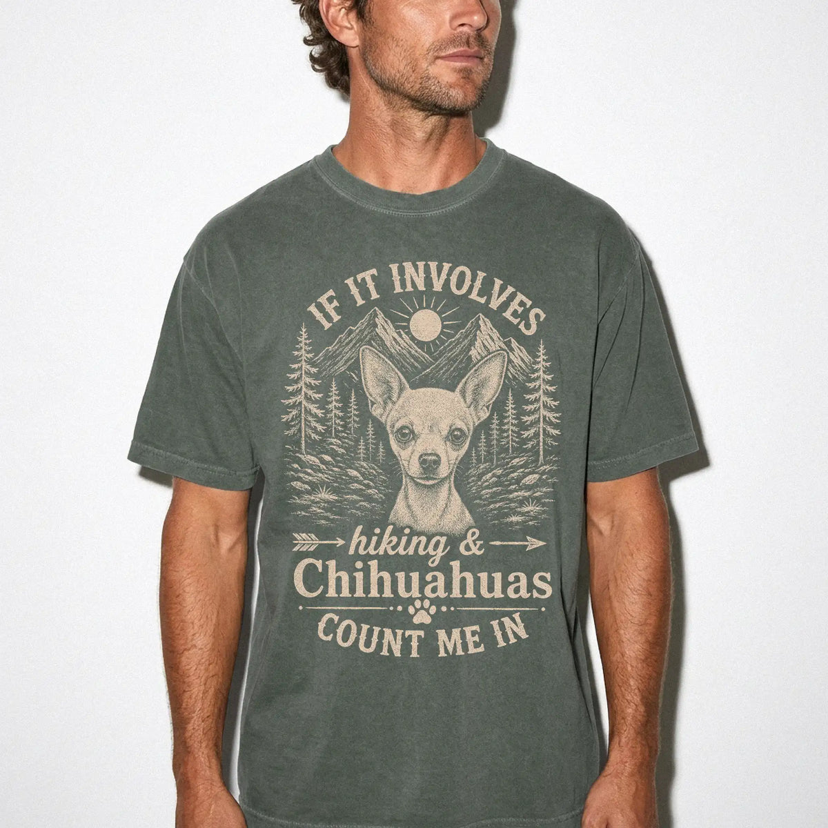Model wearing a Moss Comfort Colors® T-shirt featuring Chihuahua hiking design with mountain scenery