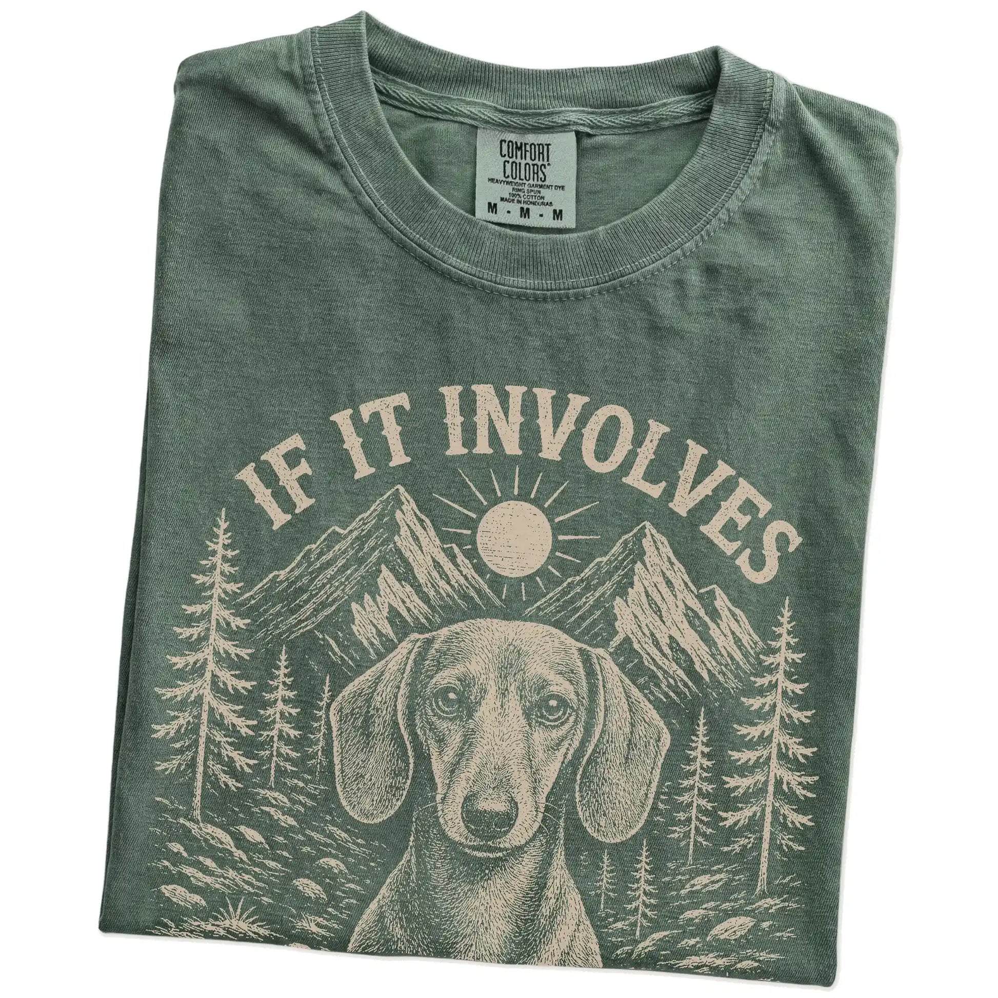 Folded Moss Comfort Colors® T-shirt showing Dachshund hiking design with mountain scenery