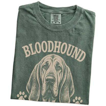 Folded Moss Comfort Colors® T-shirt showing Bloodhound design with “I Never Forget A Scent Or A Grudge” lettering