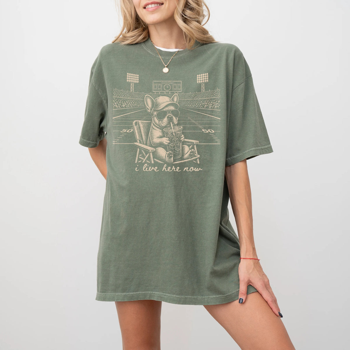 Model wearing a Moss Comfort Colors® T-shirt featuring French Bulldog claiming the football field with “I Live Here Now” lett