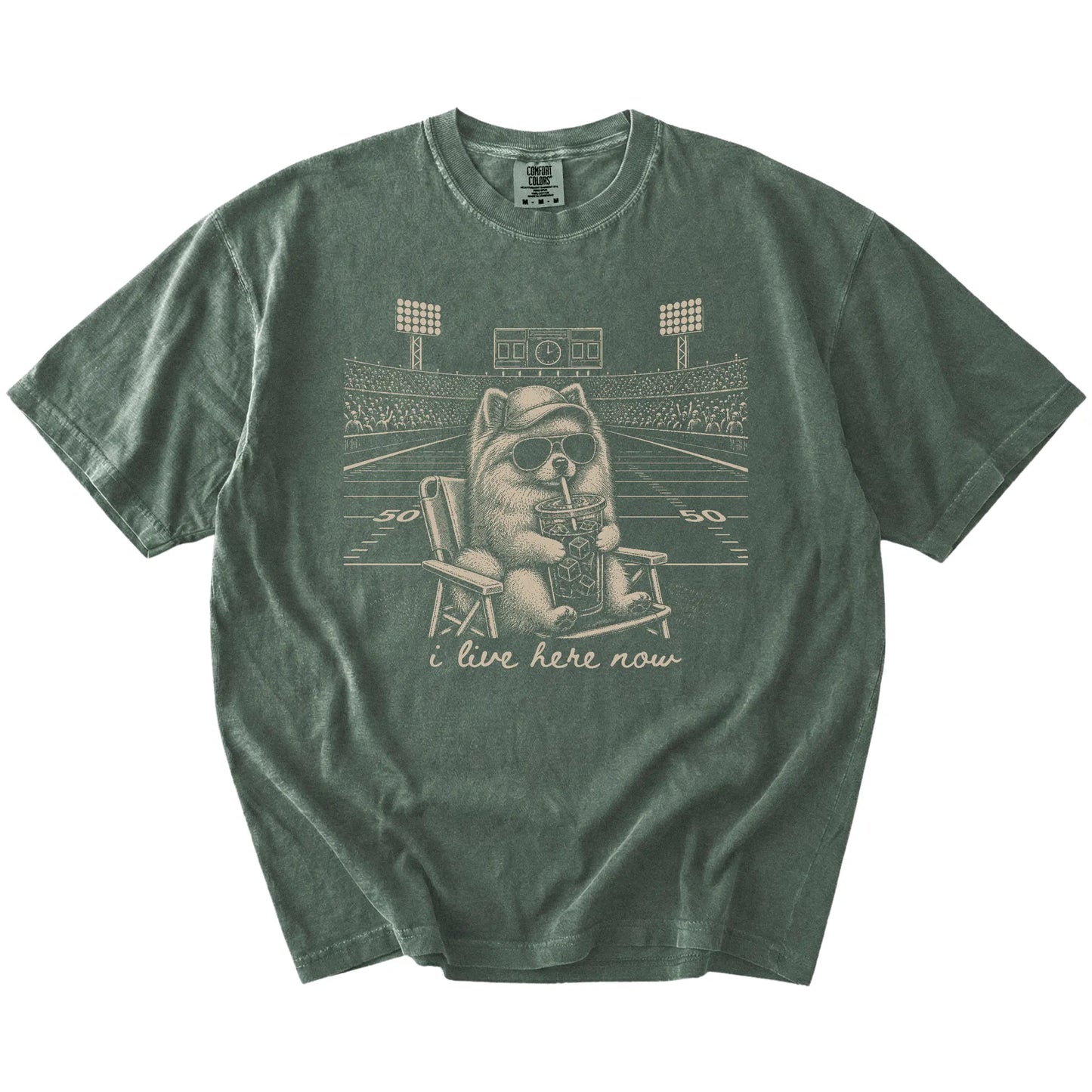 Pomeranian claiming the football field with “I Live Here Now” lettering on a Moss Comfort Colors® T-shirt