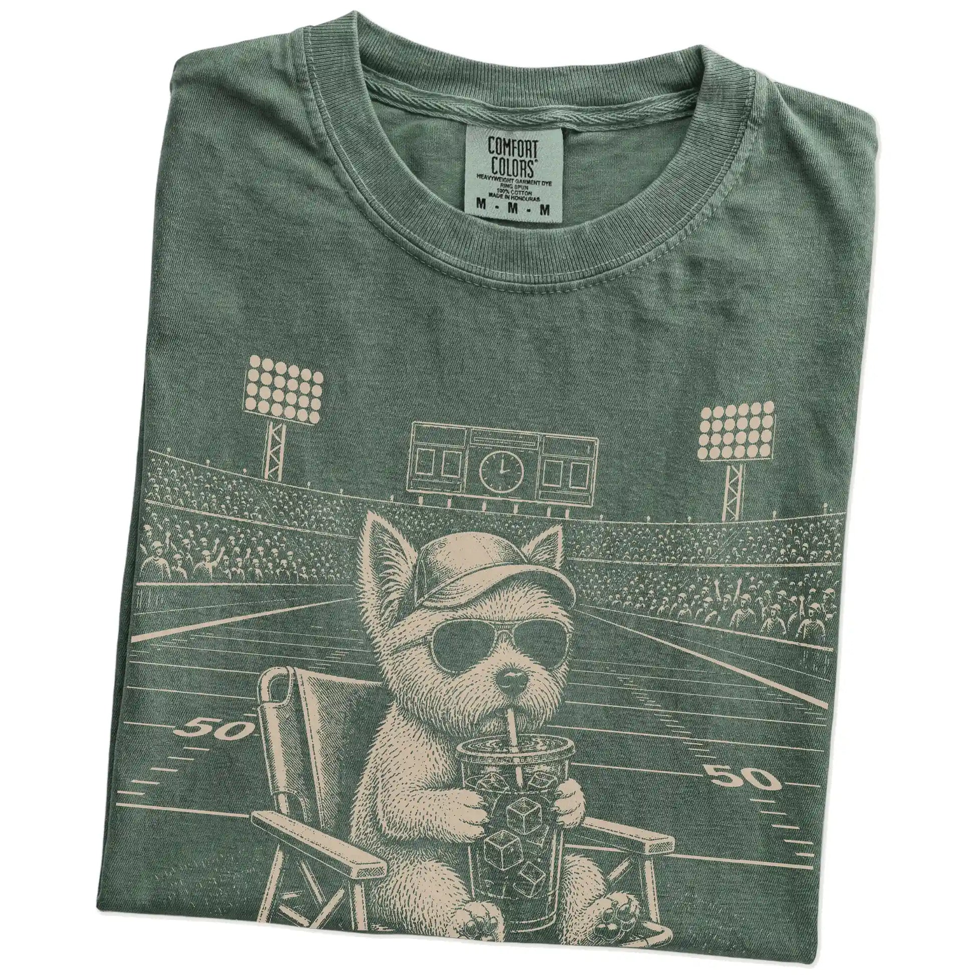 Folded Moss Comfort Colors® T-shirt showing Westie claiming the football field with “I Live Here Now” lettering