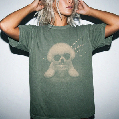 Model wearing a Moss Comfort Colors® T-shirt featuring Bichon Frise with iced coffee in a retro grunge design