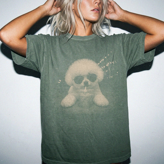 Model wearing a Moss Comfort Colors® T-shirt featuring Bichon Frise with iced coffee in a retro grunge design