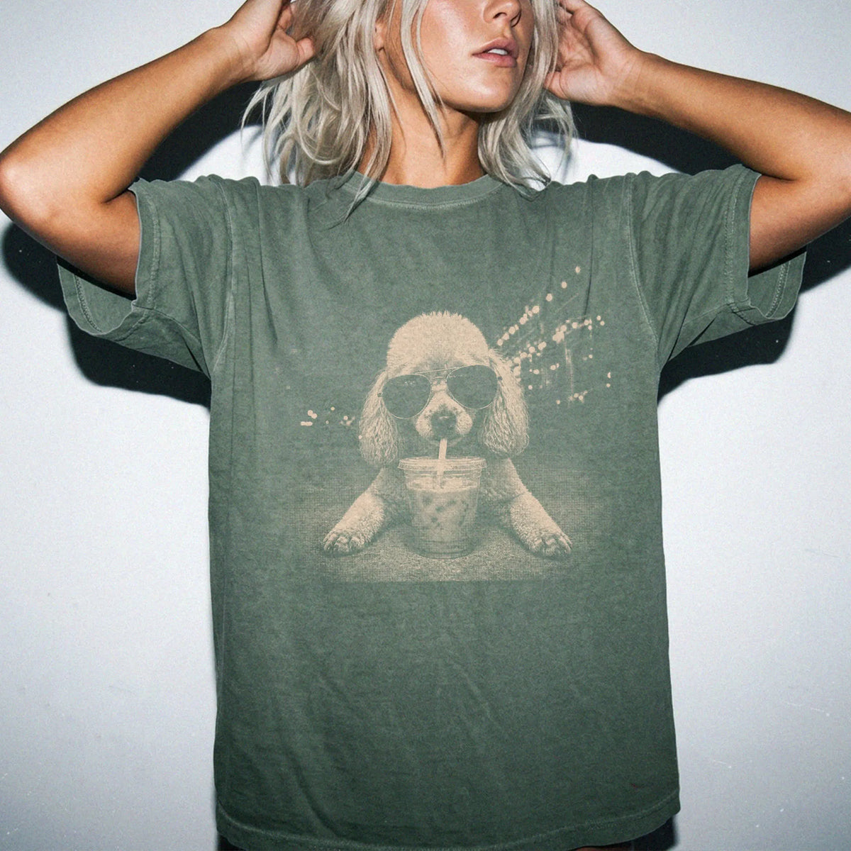Model wearing a Moss Comfort Colors® T-shirt featuring Poodle with iced coffee in a retro grunge design