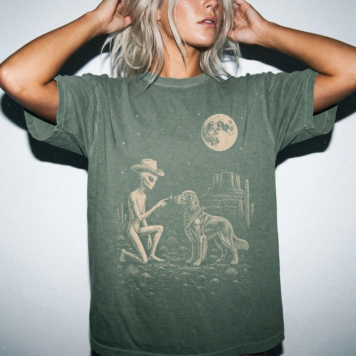 Model wearing a Moss Comfort Colors® T-shirt with cowboy alien fist-bumping a irish setter beneath the moon