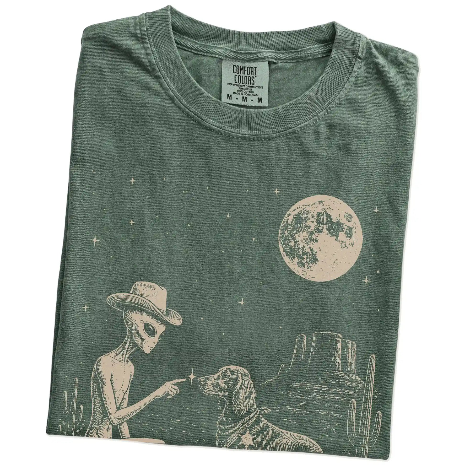 Folded Moss Comfort Colors® T-shirt showing cowboy alien fist-bumping a irish setter beneath the moon