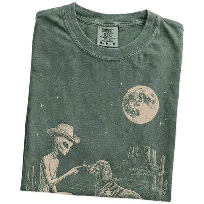 Folded Moss Comfort Colors® T-shirt showing cowboy alien fist-bumping a irish setter beneath the moon
