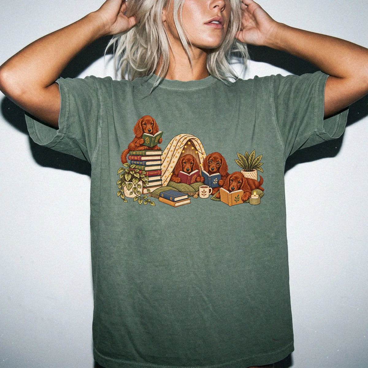 Irish Setter puppies reading books in a cozy blanket fort on a Moss T-shirt worn by a model