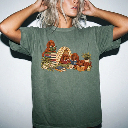 Irish Setter puppies reading books in a cozy blanket fort on a Moss T-shirt worn by a model