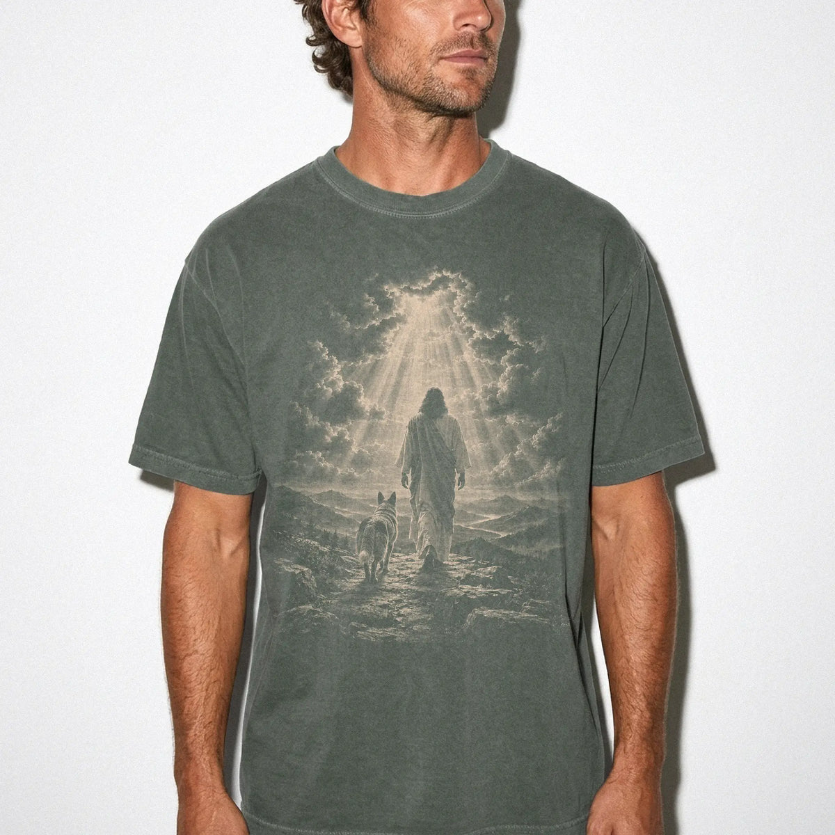 Person wearing a Moss T-shirt with Jesus walking beside a Blue Heeler beneath rays of light