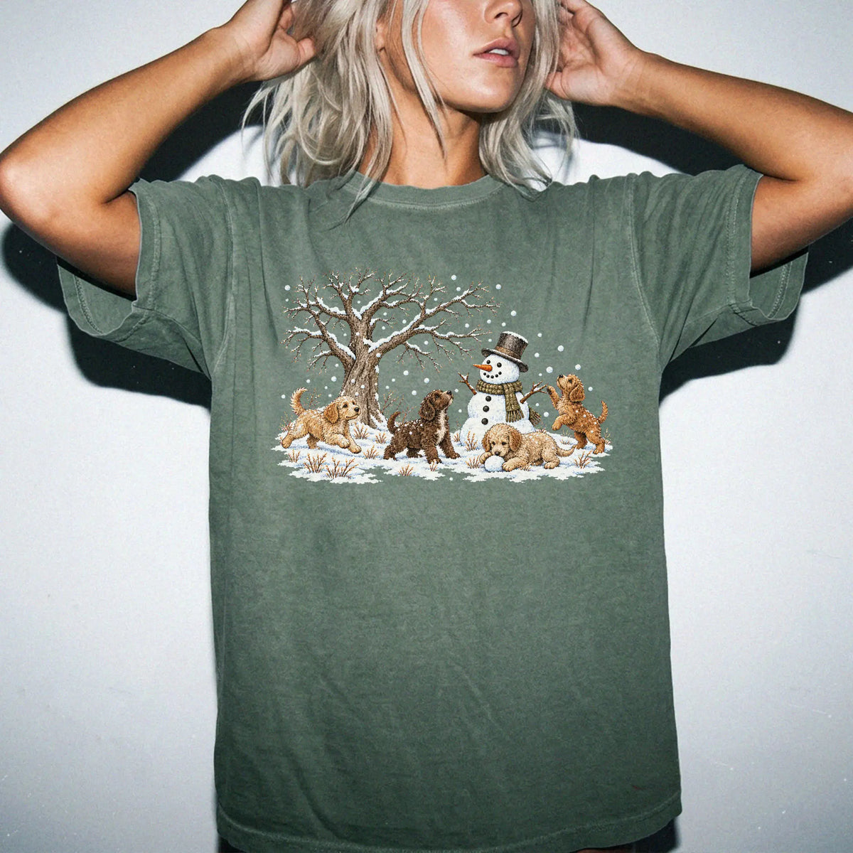 Labradoodle puppies playing in snow with a snowman on a Moss T-shirt worn by a model