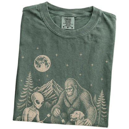Folded Moss Comfort Colors® T-shirt showing Labrador Retriever camping with Bigfoot and an alien