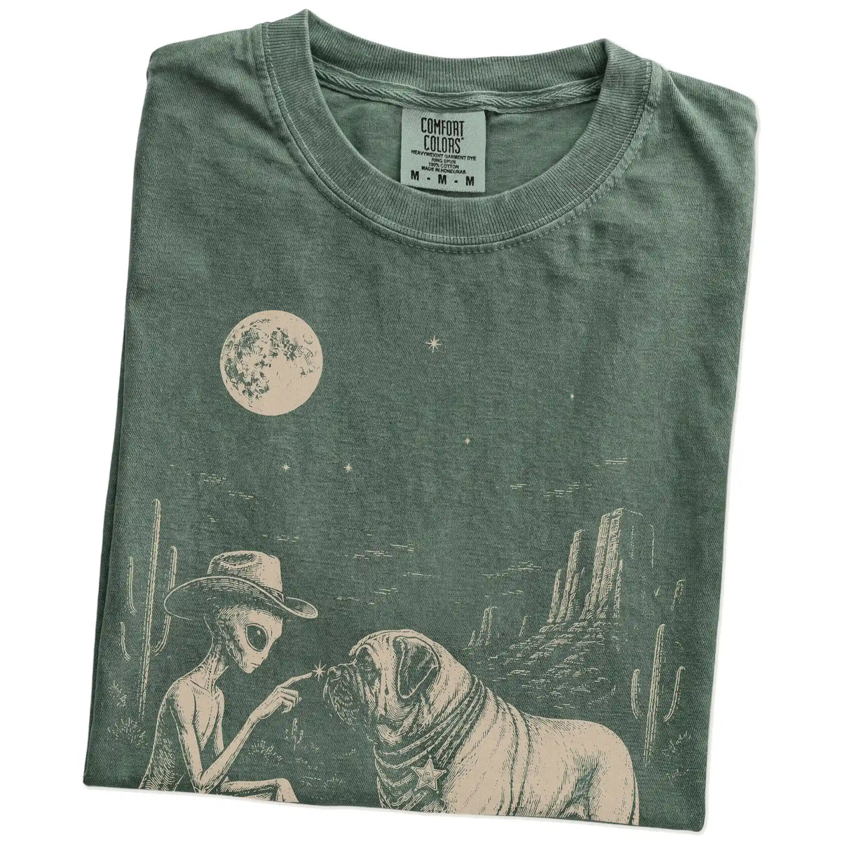 Folded Moss Comfort Colors® T-shirt showing cowboy alien fist-bumping a mastiff beneath the moon
