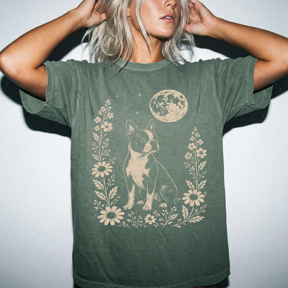 Model wearing a Moss Comfort Colors® T-shirt featuring Boston Terrier framed by flowers beneath the moon