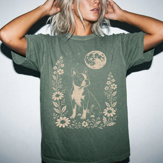 Model wearing a Moss Comfort Colors® T-shirt featuring Boston Terrier framed by flowers beneath the moon