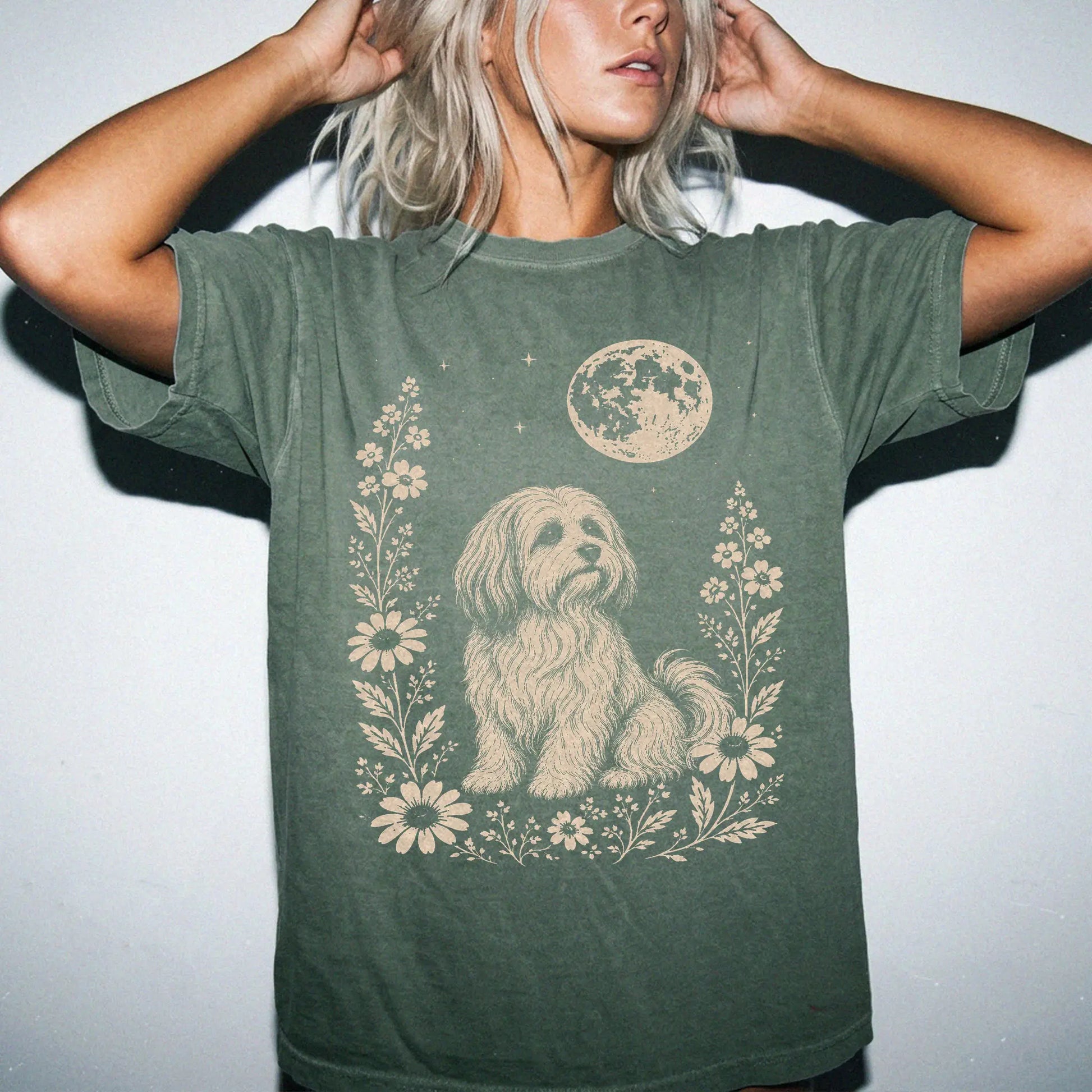 Model wearing a Moss Comfort Colors® T-shirt featuring Havanese framed by flowers beneath the moon