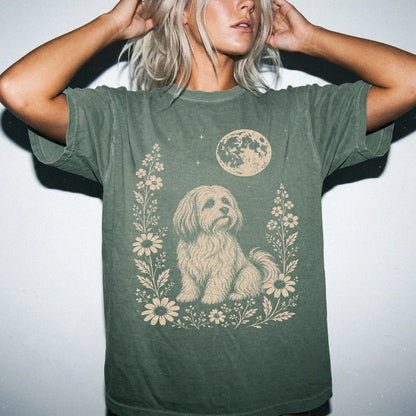 Model wearing a Moss Comfort Colors® T-shirt featuring Havanese framed by flowers beneath the moon