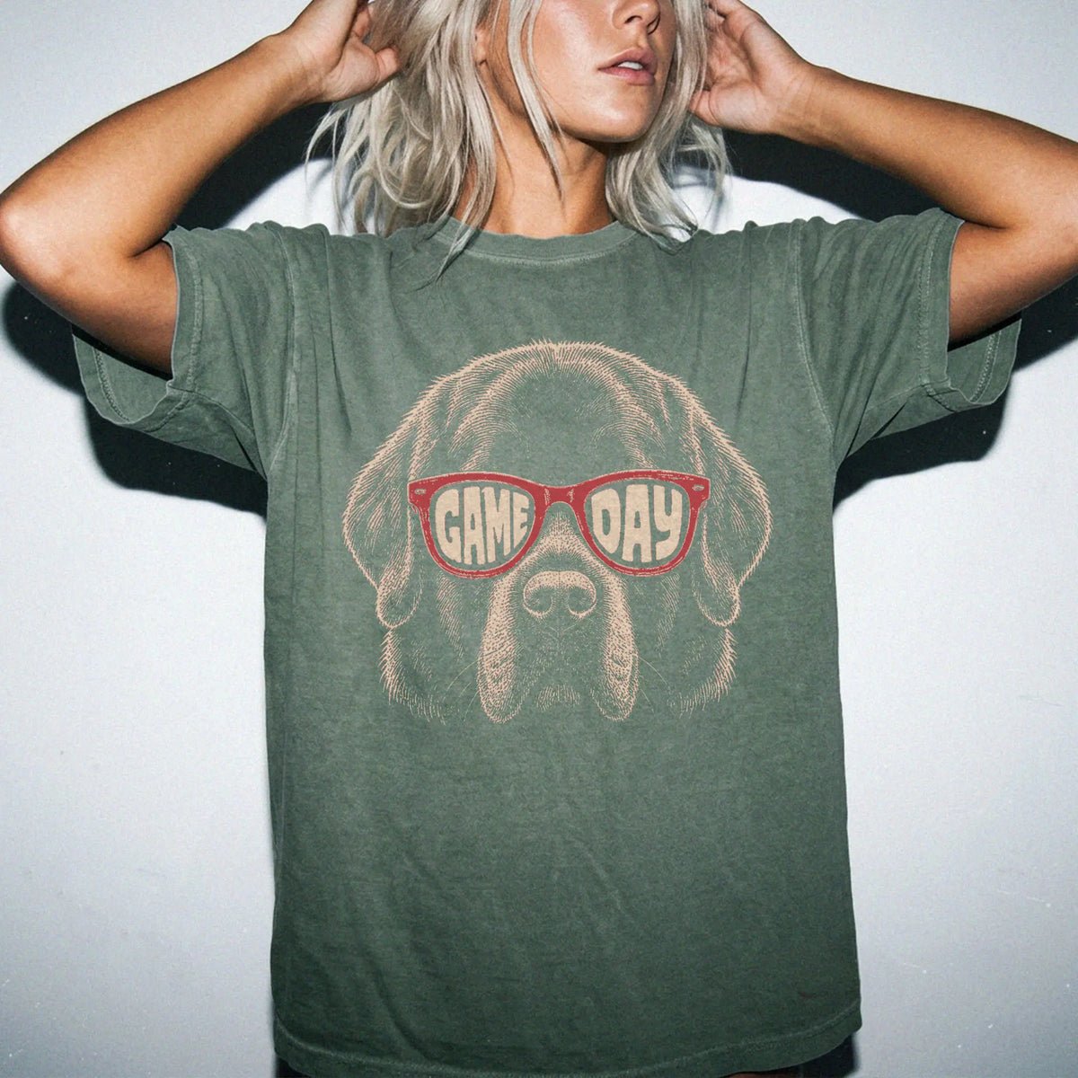 Model wearing a Moss Comfort Colors® T-shirt with newfie wearing red game day sunglasses