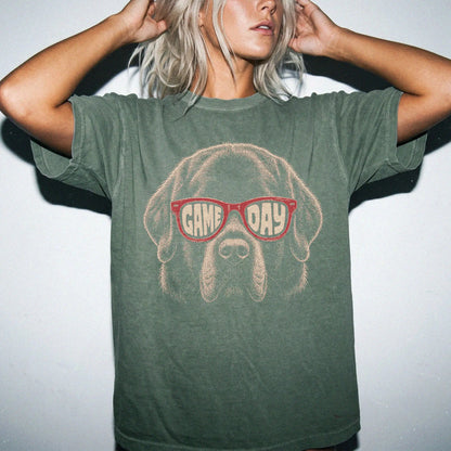 Model wearing a Moss Comfort Colors® T-shirt with newfie wearing red game day sunglasses
