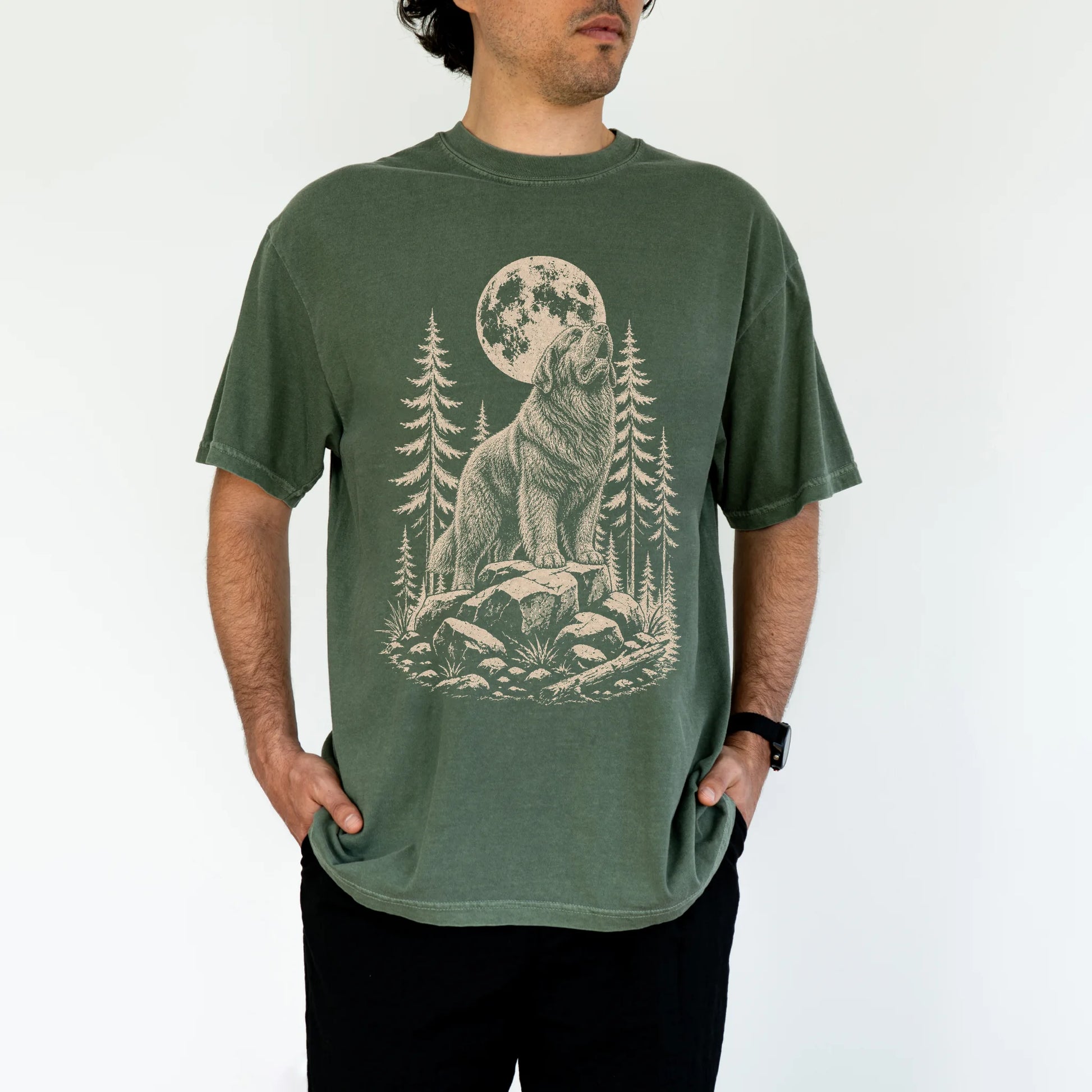 Model wearing a Moss Comfort Colors® T-shirt with a Newfie howling beneath the moon and pine trees
