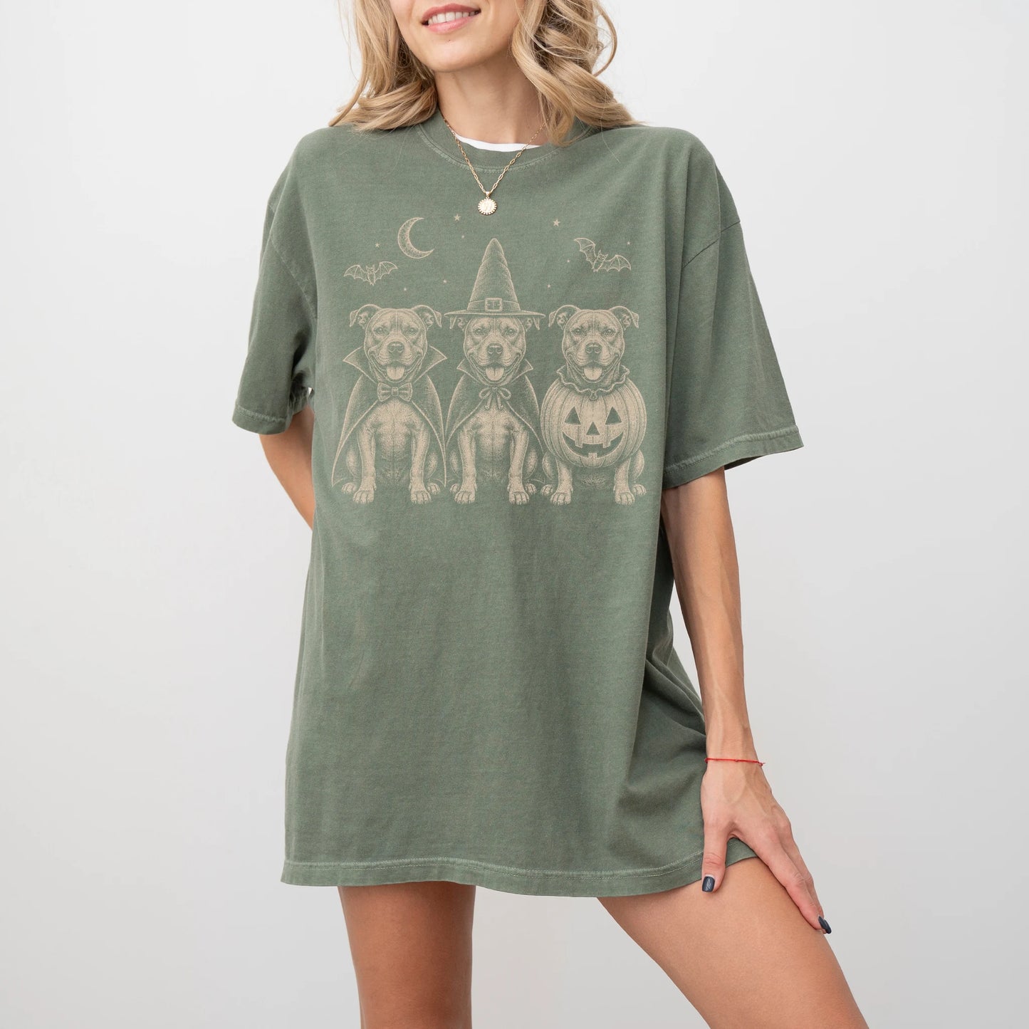 Model wearing a Moss Comfort Colors® T-shirt showing three Pitbull dogs dressed for Halloween beneath bats and a crescent moo