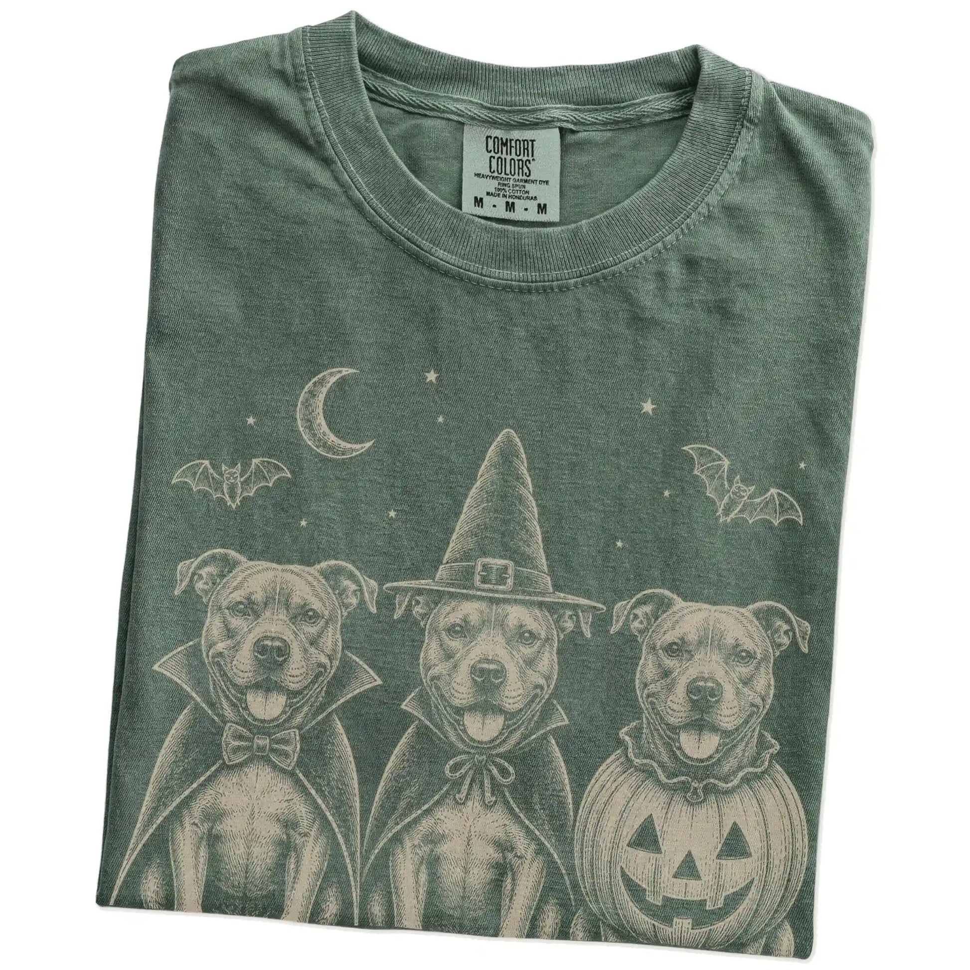 Folded Moss Comfort Colors® T-shirt showing three Pitbull dogs dressed for Halloween beneath bats and a crescent moon