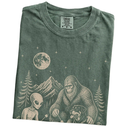 Folded Moss Comfort Colors® T-shirt showing Rottweiler camping with Bigfoot and an alien