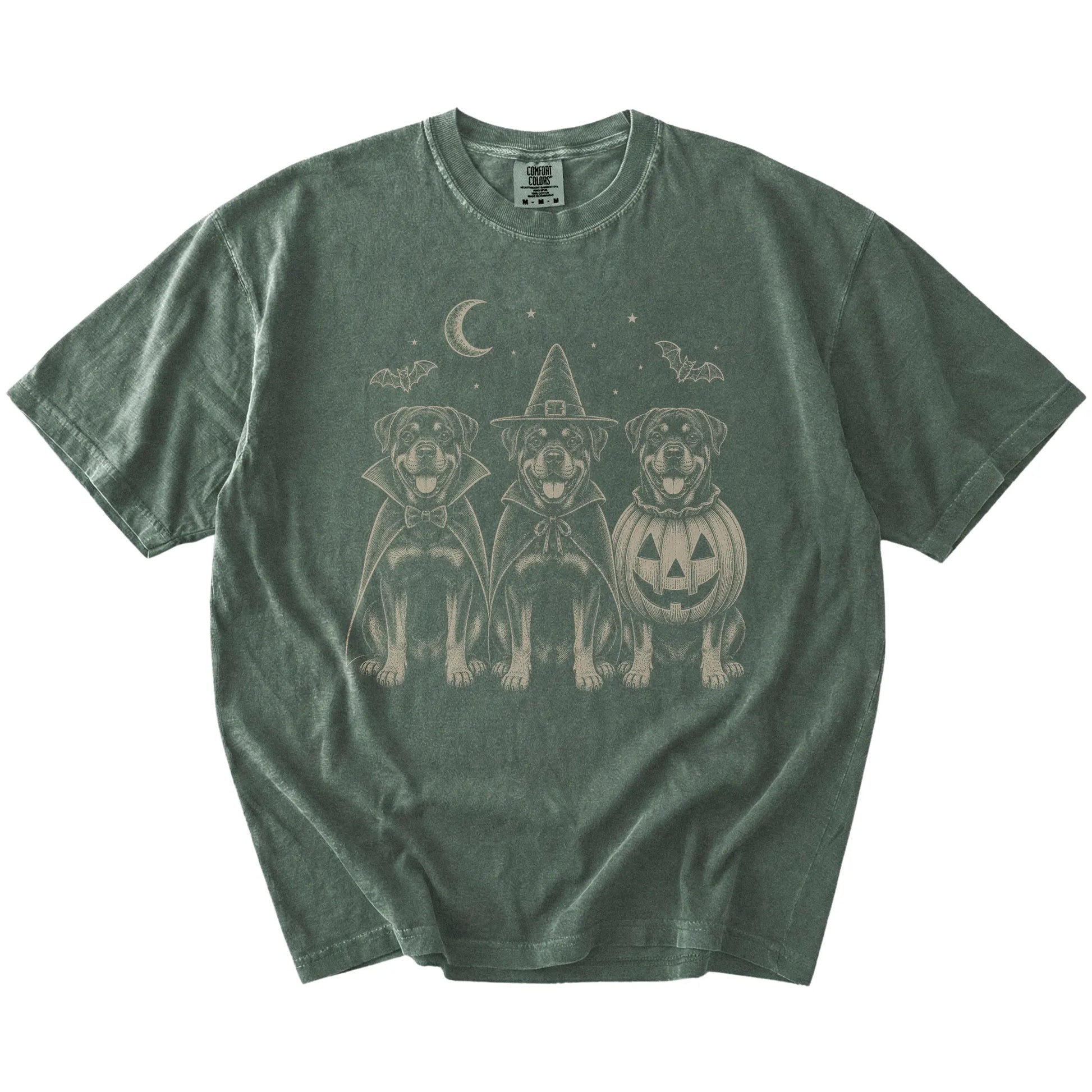 Three Rottweiler dogs dressed for Halloween beneath bats and a crescent moon on a Moss Comfort Colors® T-shirt