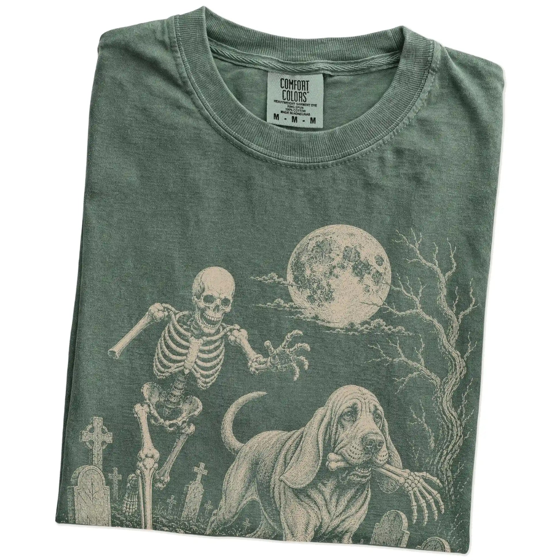 Folded Moss Comfort Colors® T-shirt showing Bloodhound running through a moonlit graveyard with a chasing skeleton
