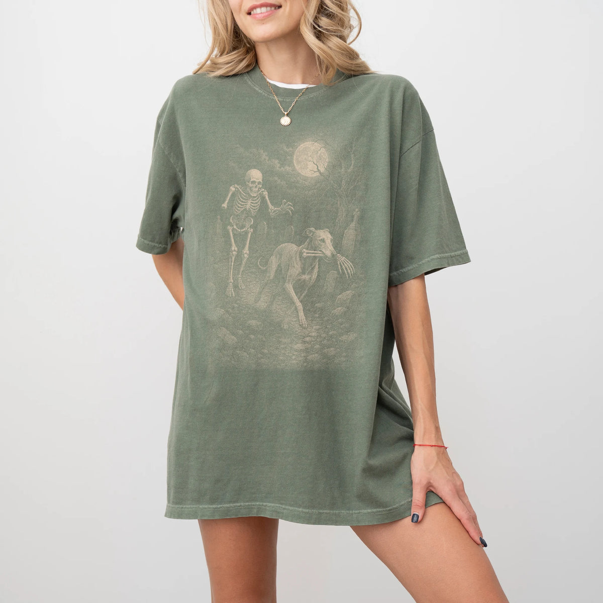 Model wearing a Moss Comfort Colors® T-shirt showing Greyhound running through a moonlit graveyard with a chasing skeleton