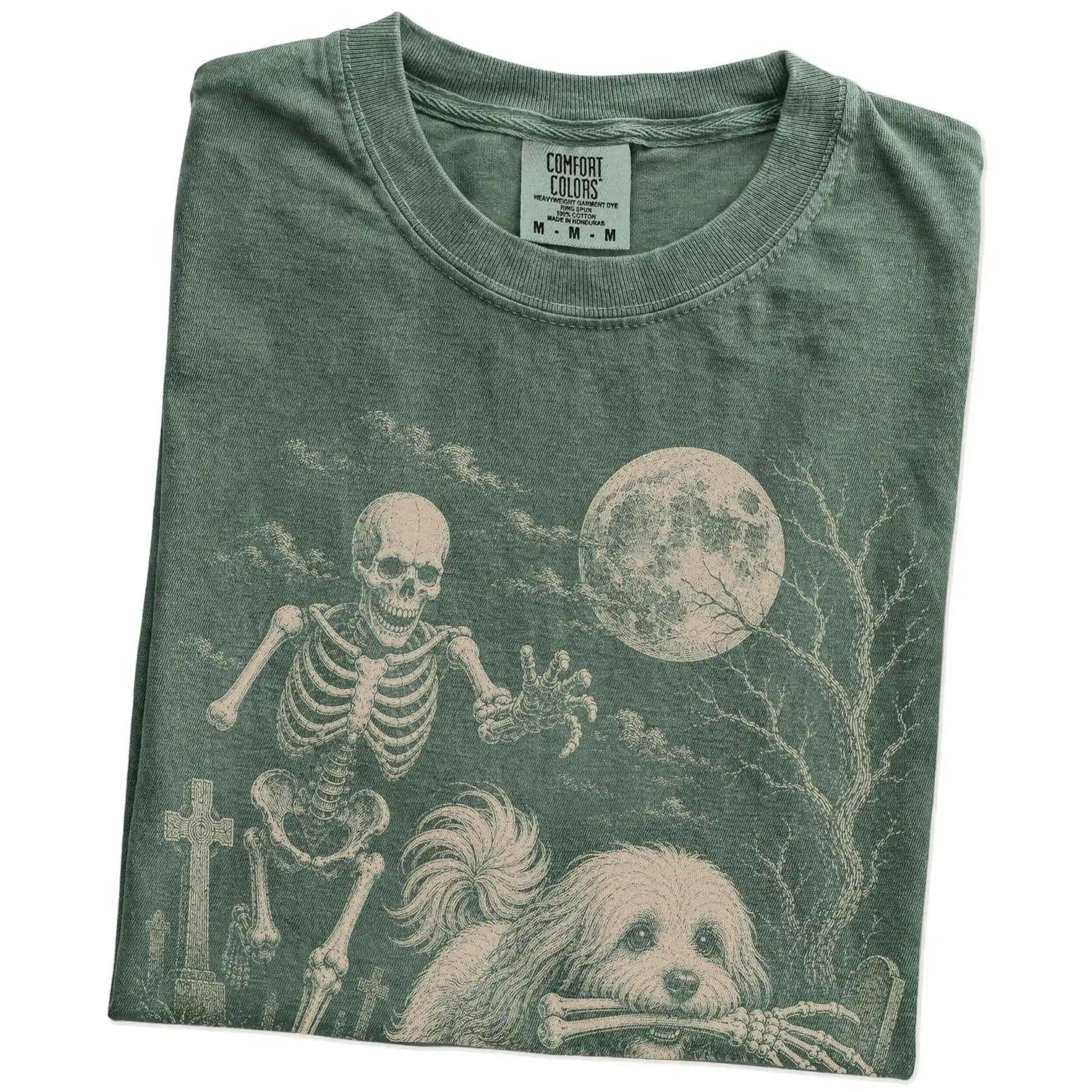 Folded Moss Comfort Colors® T-shirt showing Havanese running through a moonlit graveyard with a chasing skeleton