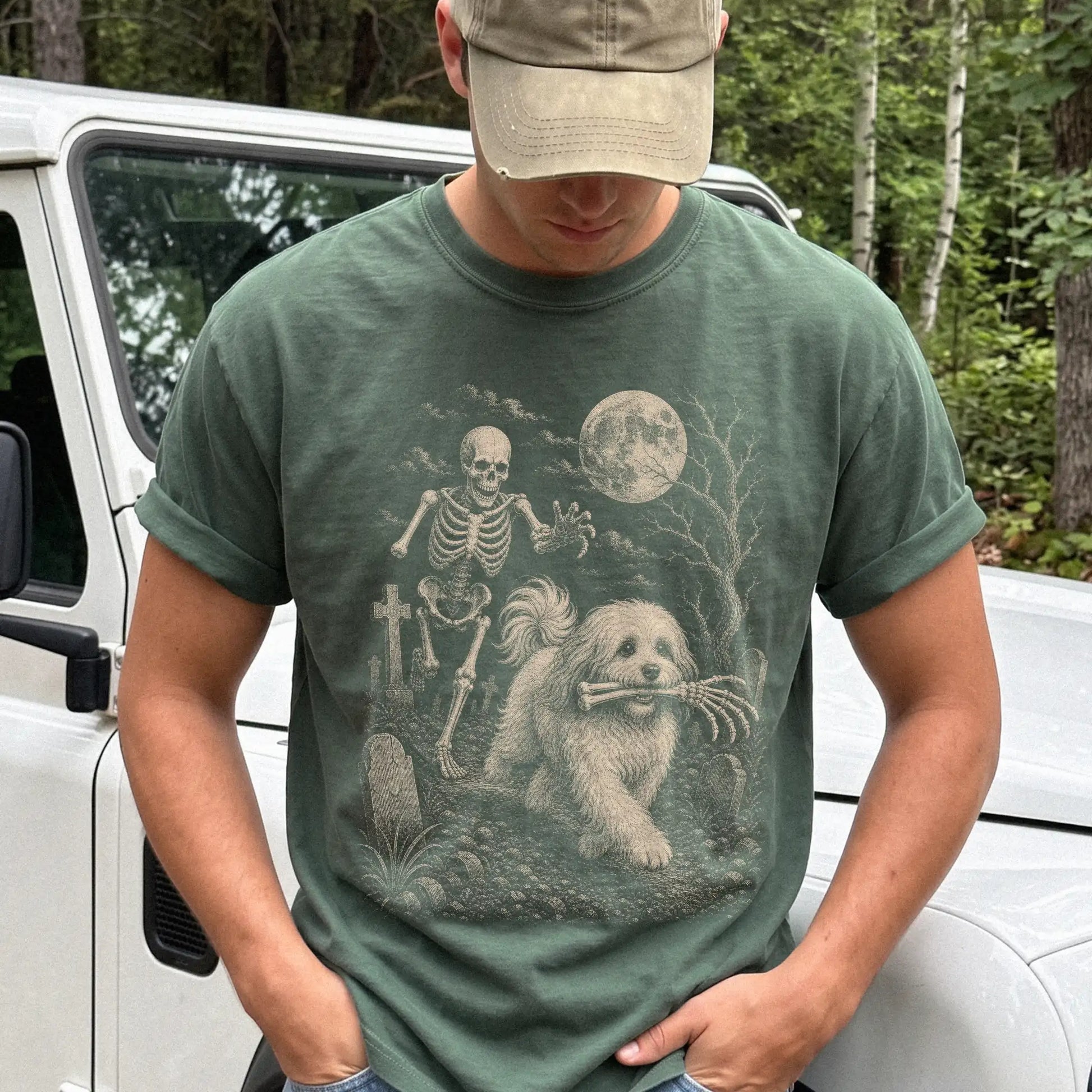 Model wearing a Moss Comfort Colors® T-shirt showing Havanese running through a moonlit graveyard with a chasing skeleton