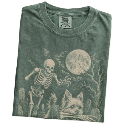 Folded Moss Comfort Colors® T-shirt showing Yorkie running through a moonlit graveyard with a chasing skeleton