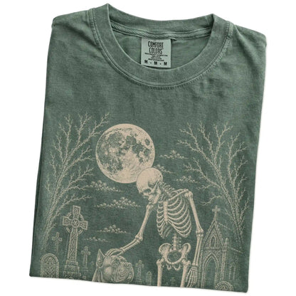 Folded Moss Comfort Colors® T-shirt showing Cane Corso sharing a quiet cemetery moment with a friendly skeleton