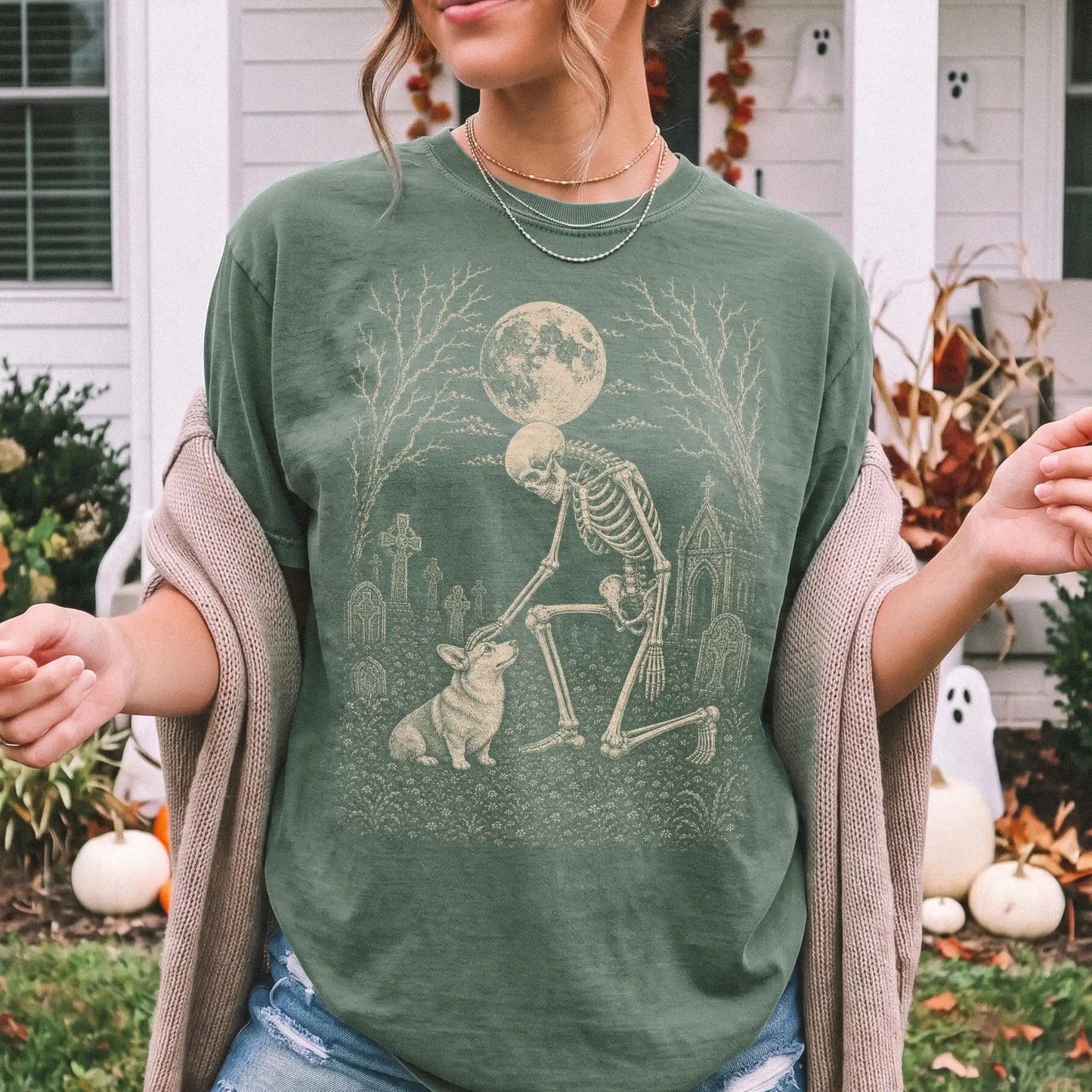 Model wearing a Moss Comfort Colors® T-shirt showing Corgi sharing a quiet cemetery moment with a friendly skeleton