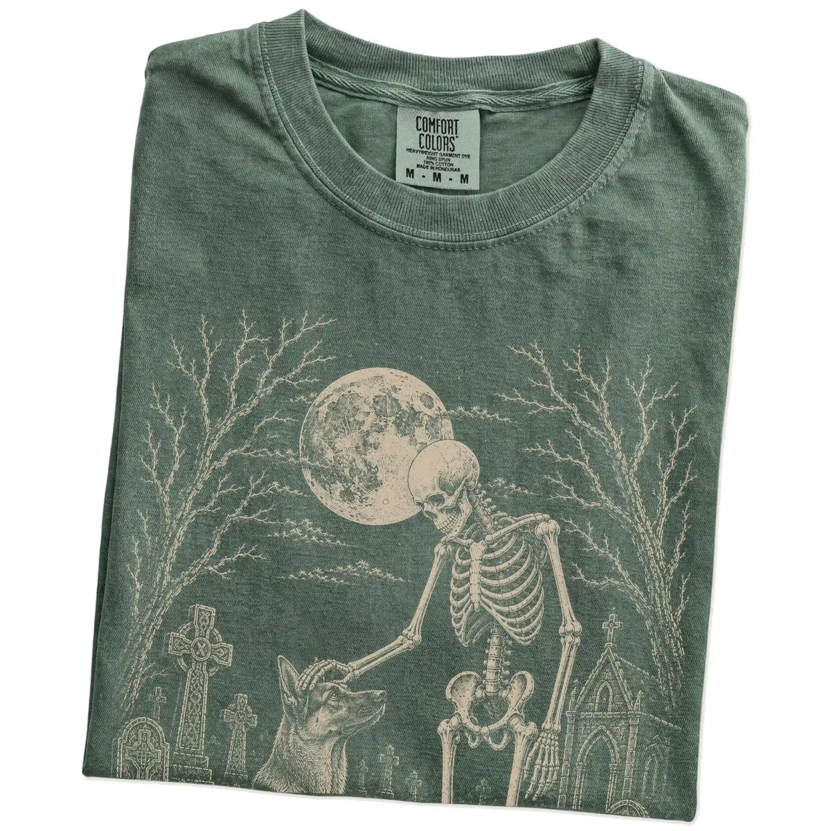 Folded Moss Comfort Colors® T-shirt showing German Shepherd sharing a quiet cemetery moment with a friendly skeleton