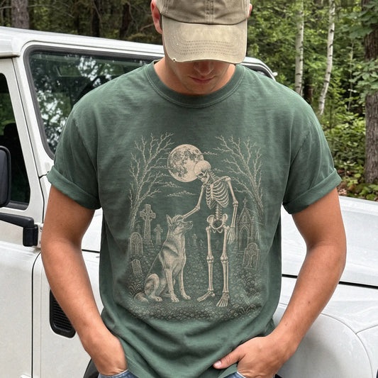 Model wearing a Moss Comfort Colors® T-shirt showing German Shepherd sharing a quiet cemetery moment with a friendly skeleton