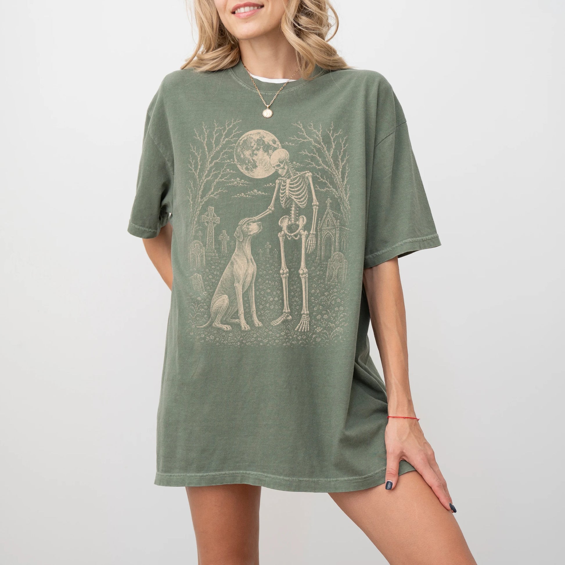 Model wearing a Moss Comfort Colors® T-shirt showing Pointer sharing a quiet cemetery moment with a friendly skeleton