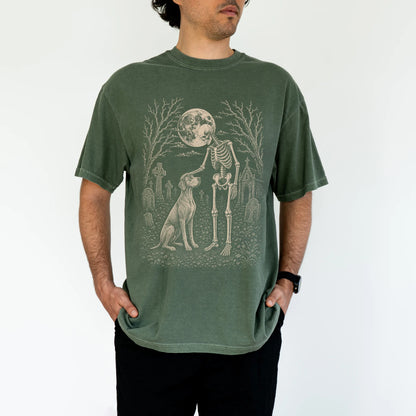 Model wearing a Moss Comfort Colors® T-shirt showing Vizsla sharing a quiet cemetery moment with a friendly skeleton