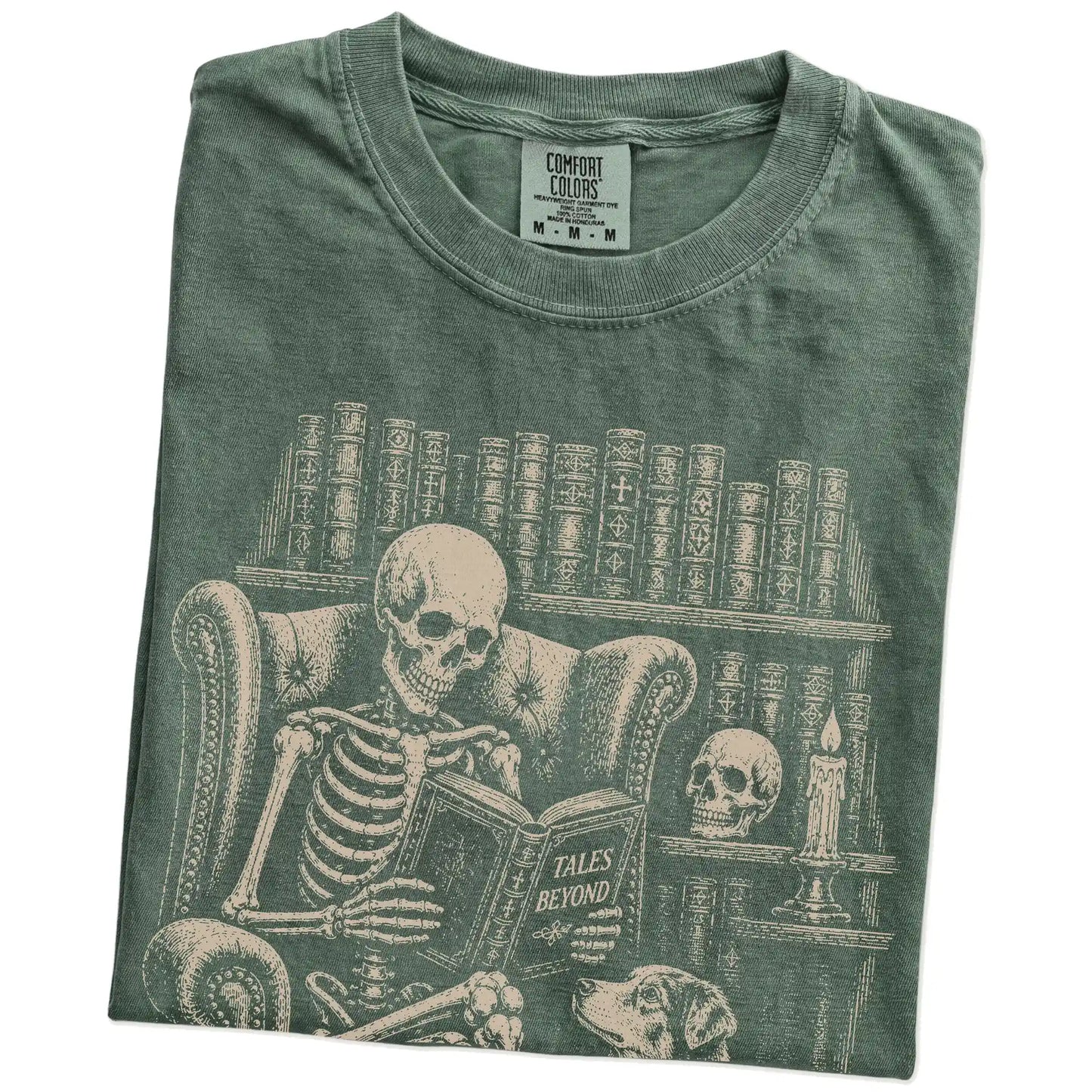 Folded Moss Comfort Colors® T-shirt showing skeleton reading in a library beside a Australian Shepherd